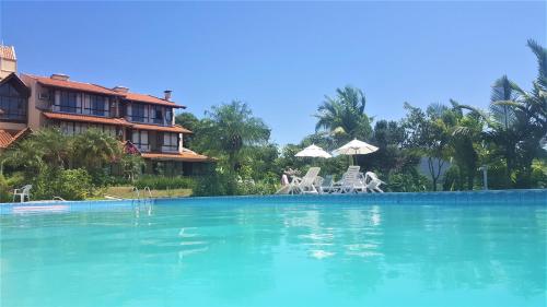 een zwembad met stoelen en parasols voor een huis bij Ilha da Galé Tourist Hotel Fazenda de Bombas in Bombinhas