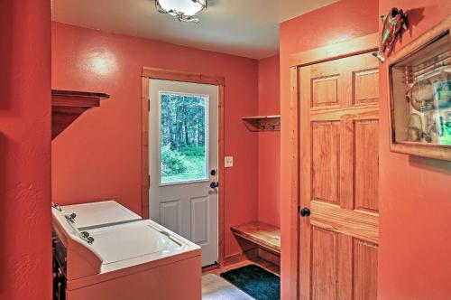 eine Küche mit orangefarbenen Wänden und einem weißen Waschbecken in der Unterkunft Secluded Birnamwood Cottage with Deck and River Views! in Birnamwood