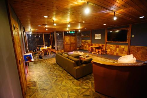 a living room with a couch and a tv at HAKUBA LODGE OMUSUBI in Otari