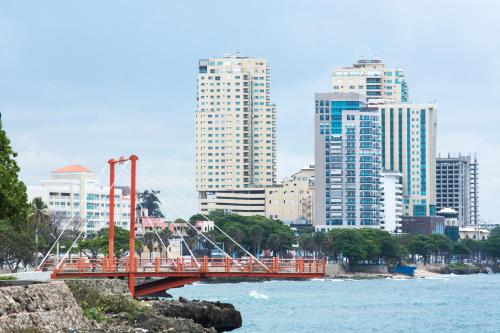 a red bridge over the water in a city at Malecon Premium Rooms & Hotel in Santo Domingo