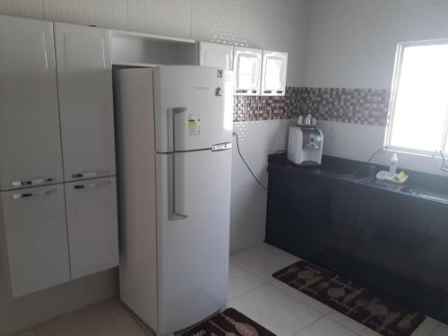 a kitchen with a white refrigerator and a window at Casa de Temporada Illôa in Canindé de São Francisco