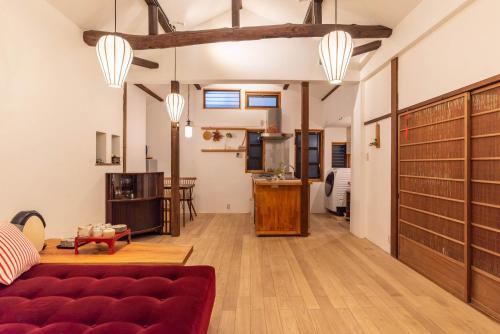 a living room with a red couch and a kitchen at back alley residence Hibi in Osaka
