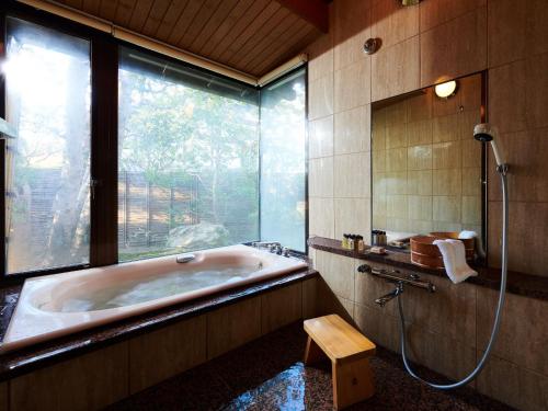 Yamaha Resort Katsuragi Kitanomaru في Fukuroi: حمام كبير مع حوض استحمام ونافذة