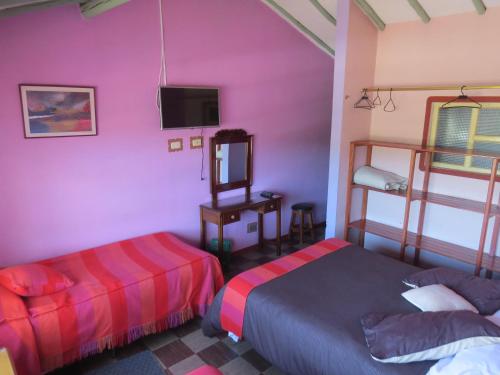 a bedroom with two beds and a tv in it at Hotel Portón De Ocetá in Monguí