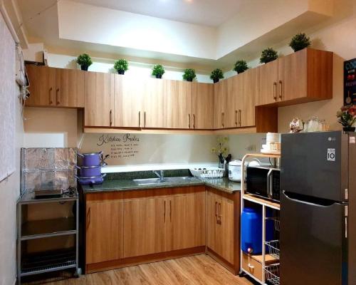 a kitchen with wooden cabinets and a black refrigerator at DMCI Bristle Ridge Condo 318 Cozy 2 Bedroom Unit in Baguio