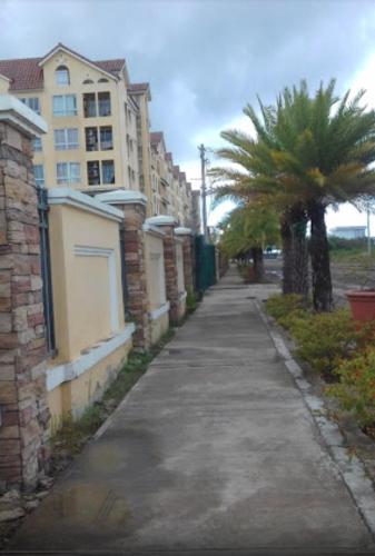 a sidewalk with a palm tree and a building at San Remo Oasis SRP Cebu in Cebu City