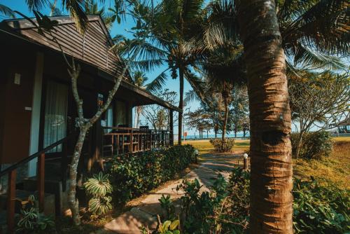 a house with a palm tree next to a sidewalk at Nana Beach Hotel & Resort in Pathiu