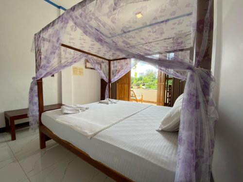 Bett mit Baldachin in einem Zimmer in der Unterkunft Aqua Blue in Arugam Bay