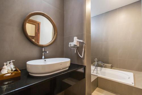 a bathroom with a sink and a mirror and a tub at Kuta Legian Villa by Kamara in Legian