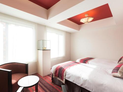 a bedroom with a bed and a table and a window at Hotel Dans Le Coeur Osaka Umeda in Osaka