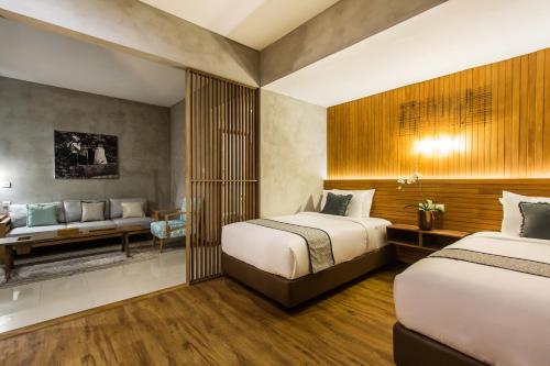 a hotel room with two beds and a couch at Kuta Legian Villa by Kamara in Legian