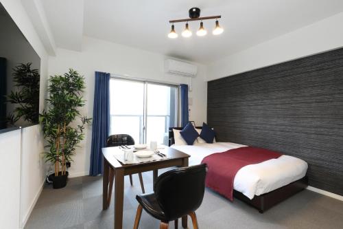 福岡市にあるThe Grand Residence Hotel Hakataのベッドと机とテーブルのある寝室