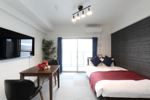 1 dormitorio con 2 camas, mesa y ventana en The Grand Residence Hotel Hakata, en Fukuoka