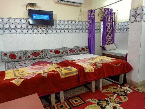 a bedroom with a bed and a tv on the wall at Kashi Annapurna Guest House in Varanasi