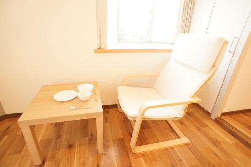 a white chair sitting next to a wooden table at Plusone Nishikoen in Fukuoka