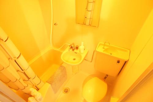 a yellow bathroom with a sink and a toilet at Plusone Nishikoen in Fukuoka