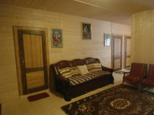 a living room with a leather couch and a door at Karpatskiy Domik Izki in Izki
