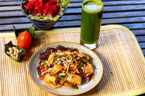 a plate of food on a table with a drink at Ubud Sari Health Resort in Ubud