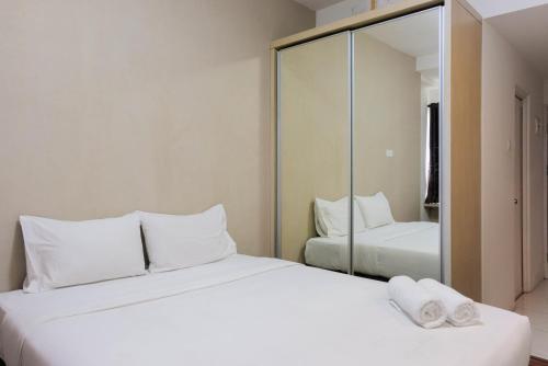 a bedroom with two beds and a mirror at Best Price Studio Apartment at Tamansari Skylounge By Travelio in Tangerang