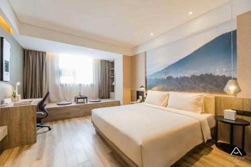 a hotel room with a large bed and a desk at Atour Hotel (Yixing Huankeyuan) in Wuxi