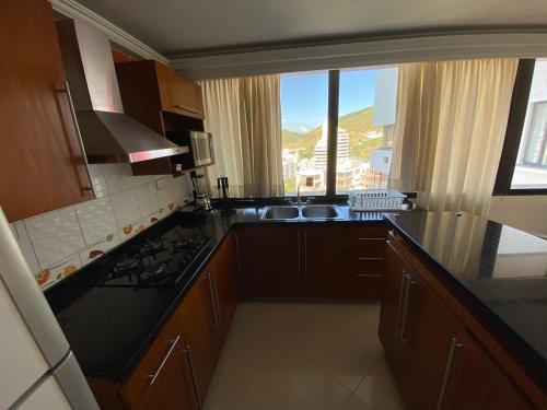 a kitchen with a sink and a counter with a window at Rivas Apartamentos Santa Marta in Santa Marta