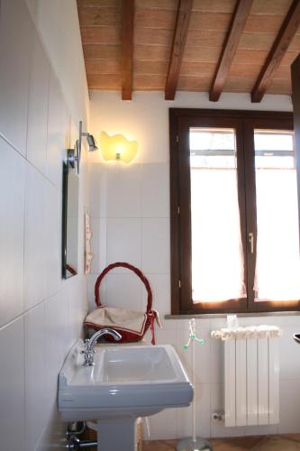 a bathroom with a sink and a chair in it at Graziosa casetta con Piscina in Castagneto Carducci
