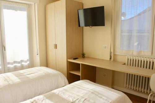 a room with two beds and a desk with a television at B&B Penak Mountain wellness in Aprica