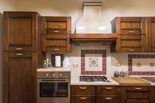 a kitchen with wooden cabinets and a stove top oven at Palazzo Arcidiacono - luxury holidays in Catania