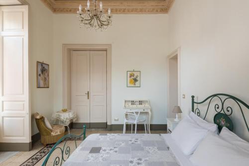 a bedroom with a bed with a chandelier and a desk at Palazzo Arcidiacono - luxury holidays in Catania
