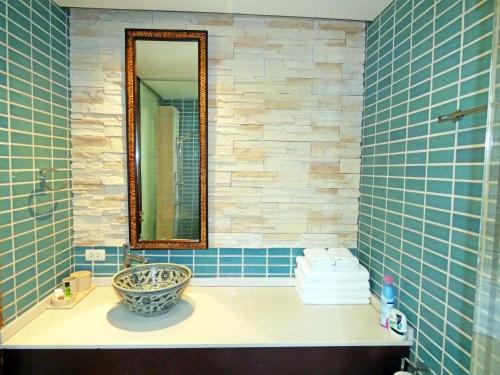 uma casa de banho com lavatório, espelho e azulejos azuis em The Beach Condo em Ko Chang