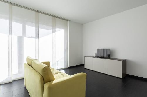 a living room with a yellow couch and a tv at Roggia Apartments by Quokka 360 - central flats with parking space in Lugano