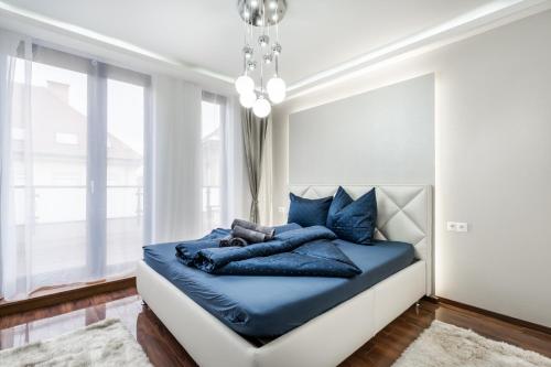 a bed with blue pillows in a room with a window at Kiraly 44 Luxury Apartment in Budapest