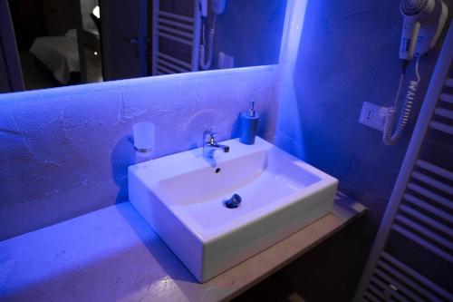 La salle de bains est pourvue d'un lavabo blanc dans une chambre bleue. dans l'établissement Graffiti B&B Apartments, à Corato