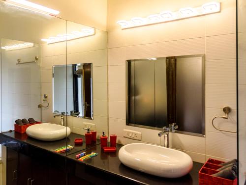 a bathroom with two sinks and two mirrors at Beautiful Apartments at Tarudhan Valley Golf Resort, Manesar in Gurgaon