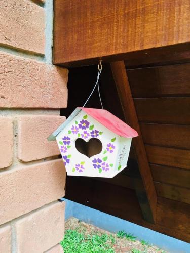 a bird house with a heart on it hanging from a wall at Chalés Amabilis in Monte Verde