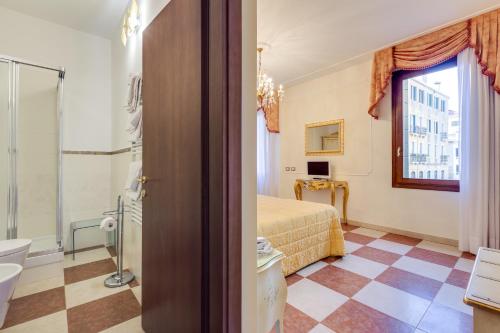 ヴェネツィアにあるホテル アット レオナールのベッドとバスルーム付きのホテルルームです。