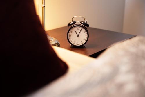 an alarm clock sitting on a table next to a bed at Villa am Park in Meiningen