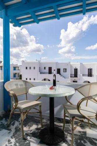 a table with two chairs and a bottle of wine on a balcony at Flora Apartments & Studios in Agia Anna Naxos