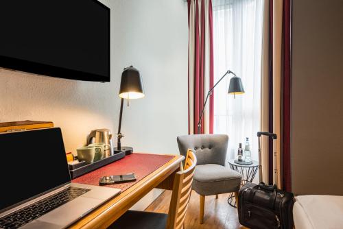 a hotel room with a desk with a laptop and a chair at Mercure Hotel Berlin Zentrum Superior in Berlin