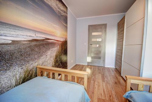 a bedroom with a painting of the beach at HelApart - Bałtyk II in Hel