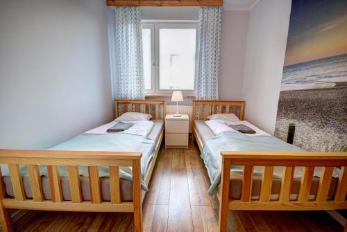 two twin beds in a room with a window at HelApart - Bałtyk II in Hel