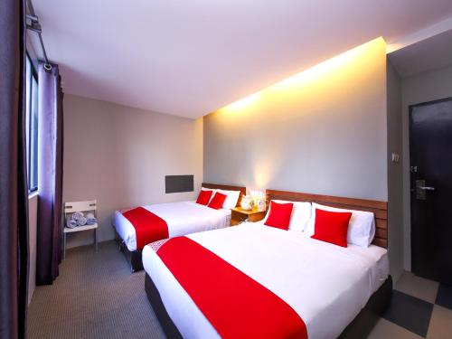 two beds in a hotel room with red and white sheets at Super OYO 910 Hills Residence in Kuching