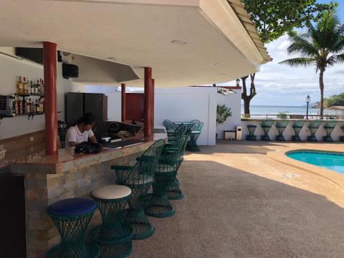 Eine Frau, die an einer Bar neben einem Pool sitzt. in der Unterkunft Out Back in Olongapo