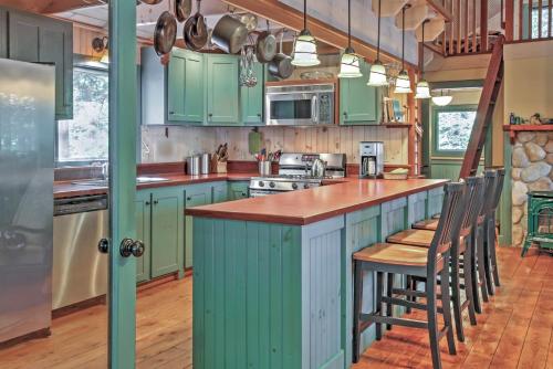 a kitchen with green cabinets and a counter with chairs at Waterfront Denmark Complex with Dock on 12 Acres! in Denmark