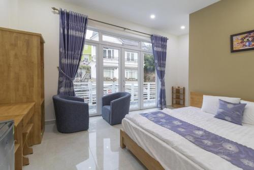 a bedroom with a bed and two chairs and a window at MrLee Dalat House in Da Lat