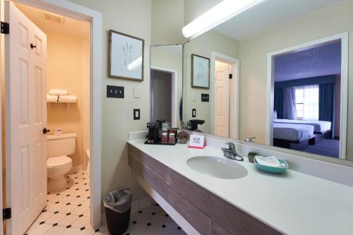 y baño con lavabo, aseo y espejo. en San Mateo Inn, en Albuquerque