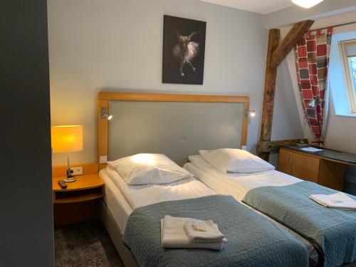 a hotel room with two beds and a table with a lamp at Hotel Willa Starosty in Międzyrzecz