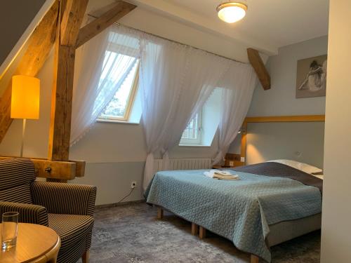 a bedroom with a bed and two windows and a table at Hotel Willa Starosty in Międzyrzecz