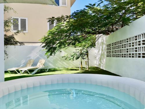 una piscina en el patio trasero de una casa con un árbol en The Blue Corner Apartments, en Puerto de la Cruz
