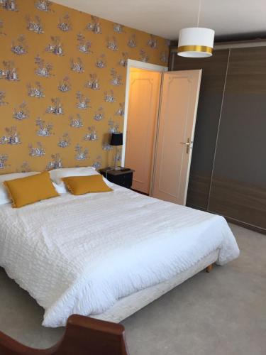 a bedroom with a white bed with a yellow wall at Coeur Deauville Grand 3 pièces avec Parking in Deauville